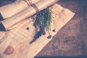 A wooden table displays lavender flowers and a parchment sheet