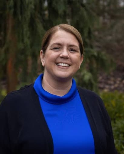 Headshot of woman smiling with trees behind her