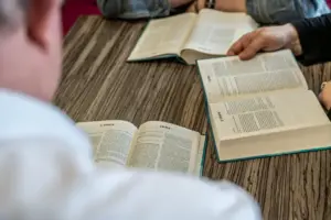 three people at a table with their bibles opened to 3 john